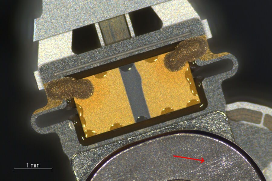 Zoom-in of the indicated area in Fig. 3a showing more detail of the same hard drive read-write head and actuator arm. There are scratches on the arm’s metal surface near the head (arrow).