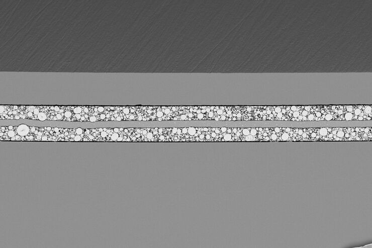 [Translate to German:] SEM image of the full Li-NMC electrode sample, showing the two porous layers and the metal film at the center of the structure.