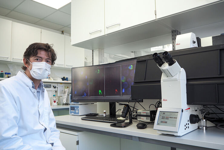 Der Direktor des Instituts für Virologie auf dem Campus Charité Mitte, Prof. Dr. Christian Drosten, am Laborarbeitsplatz mit dem THUNDER Imager 3D Live Cell von Leica Microsystems.