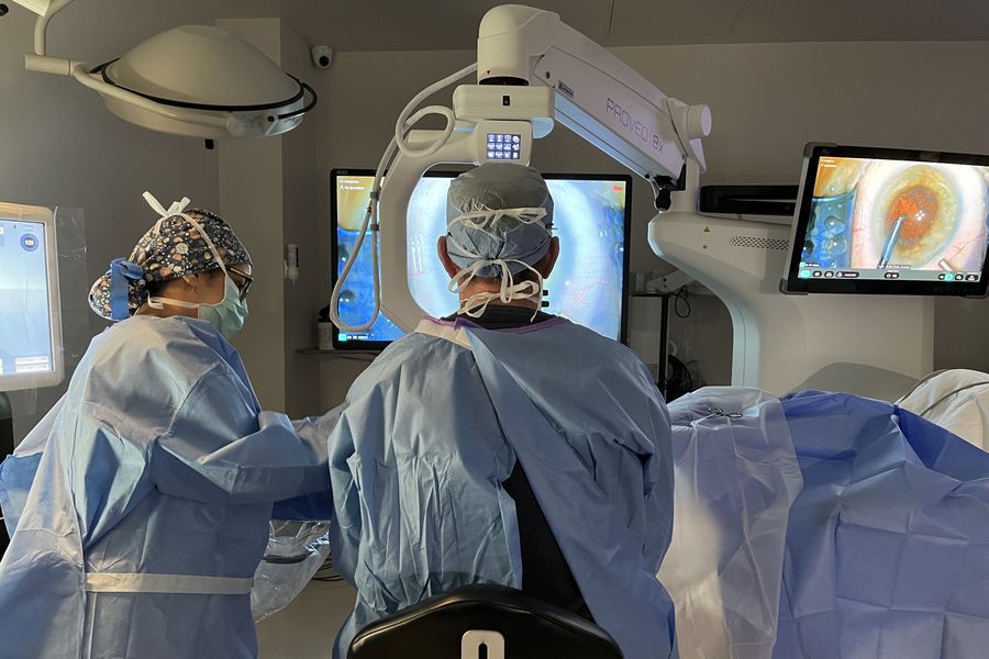 Heads‑up ophthalmic surgery using a Proveo 8x 3D digital microscope, with surgeon viewing the procedure on monitors in an ergonomic seated position.