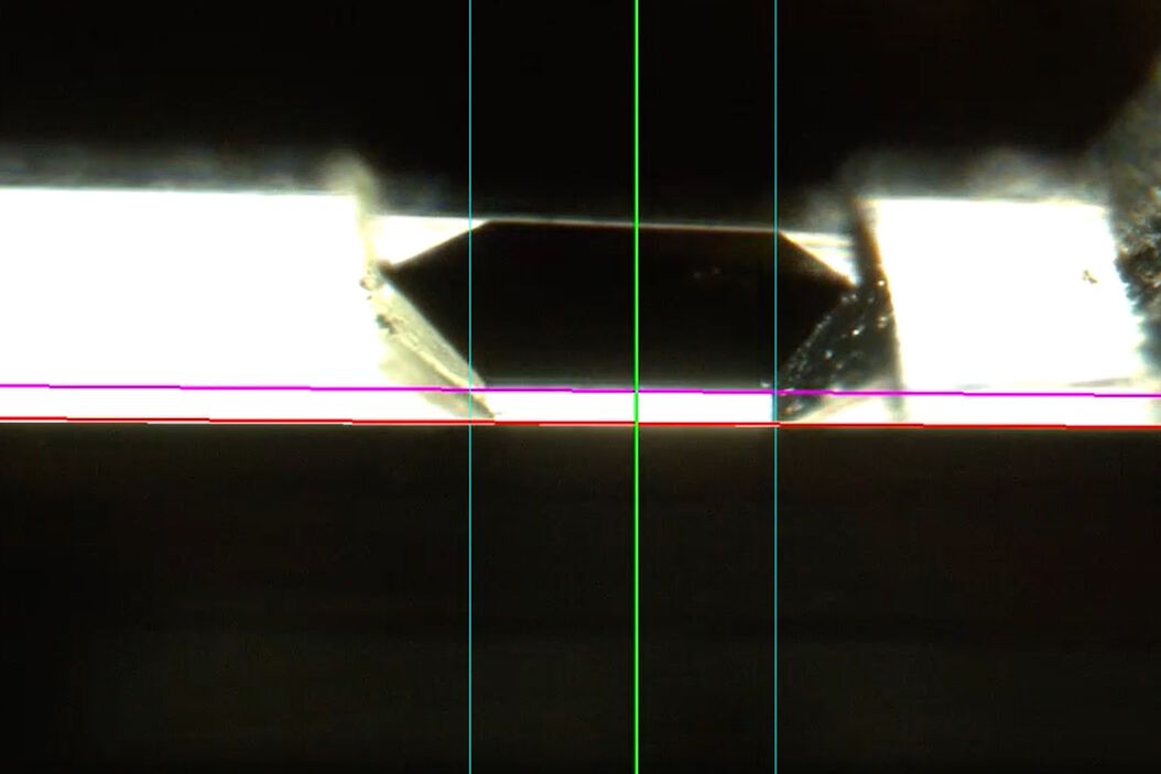 [Translate to chinese:] Camera image during auto alignment. The feedback lines indicate if the correct edges in the image are detected. Green: Vertical center line; Magenta: Upper edge of the light gap; White: Lower edge of the light gap (not visible here, falling together with red line); Red: Knife edge; Blue: Left and right edge of the block face being automatically detected. Camera_image_during_auto_alignment_UC_Enuity.jpg