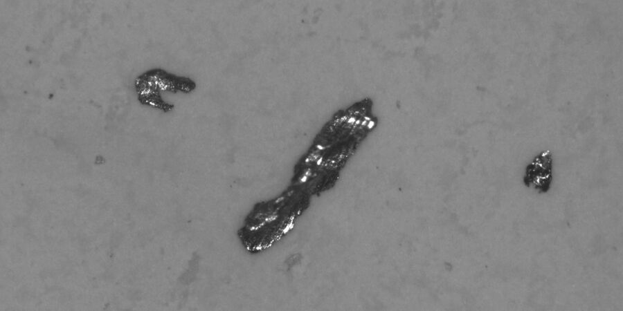 Metallic particles present on a filter after extraction from a component.