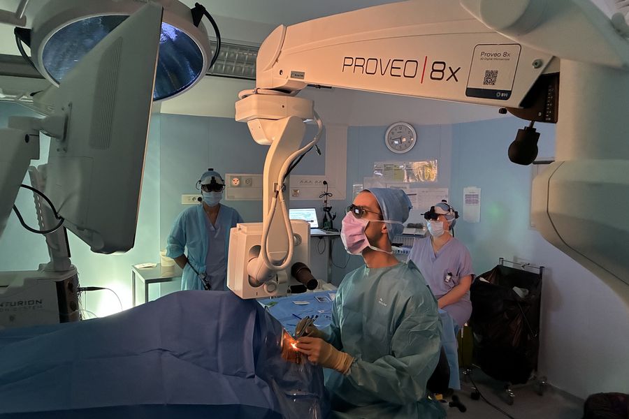 Ophthalmic surgery performed using a Proveo 8x 3D digital microscope, with multiple team members viewing the procedure simultaneously through shared 3D visualization using 3D glasses, 3D monitors, and the MyVeo surgical headset, supporting collaboration and training in the operating room.